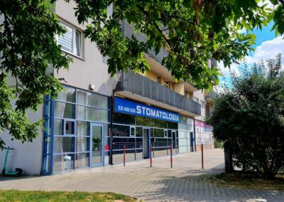 Budynek gabinetu stomatologicznego Amed w Krakowie w Nowej Hucie, widoczny od frontu, z dużymi oknami i niebieskim szyldem.